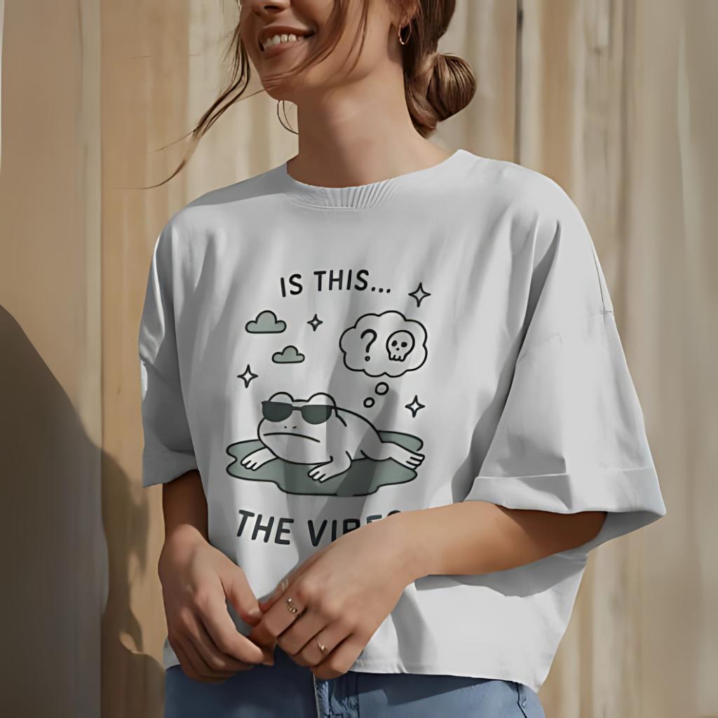 Woman wearing an oversized white t-shirt with a funny frog meme graphic and the text “Is this the vibe?”